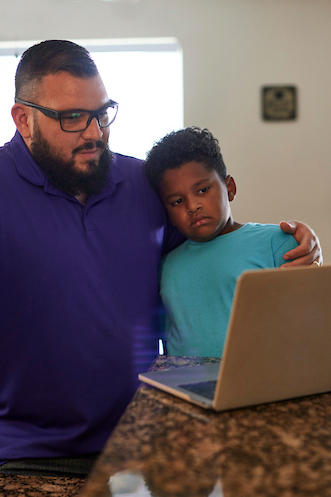 A father hugging his son during a telehealth visit