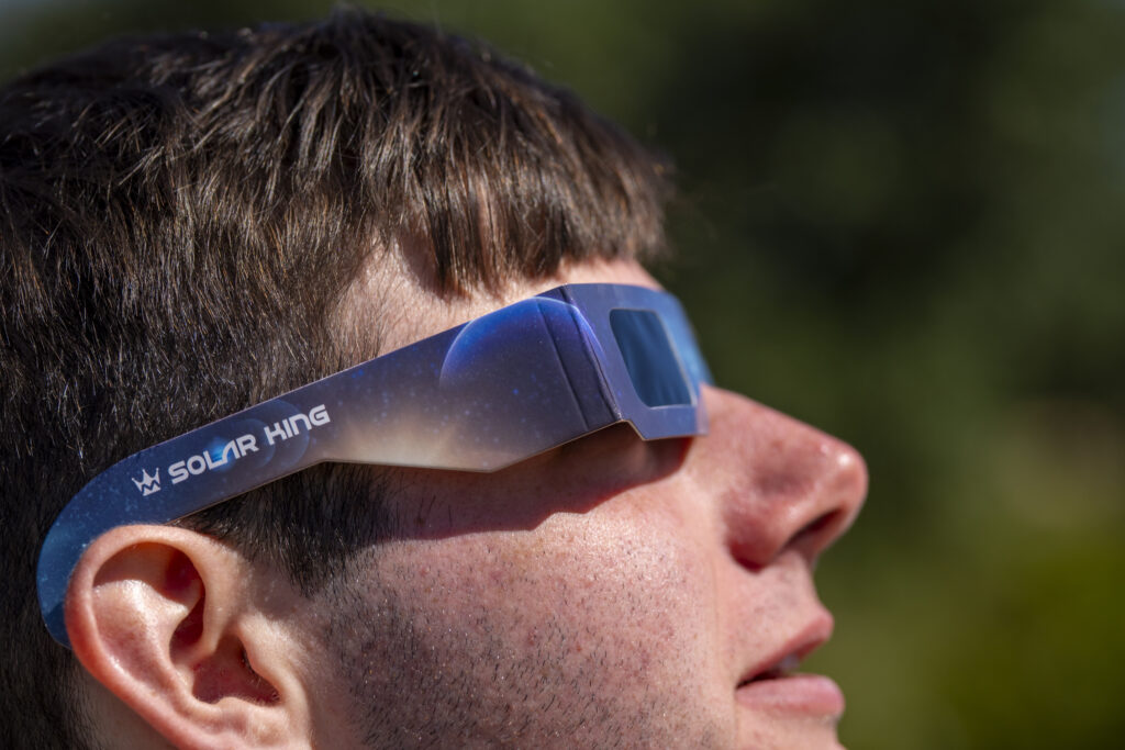 A person wearing special solar eclipse viewing glasses.